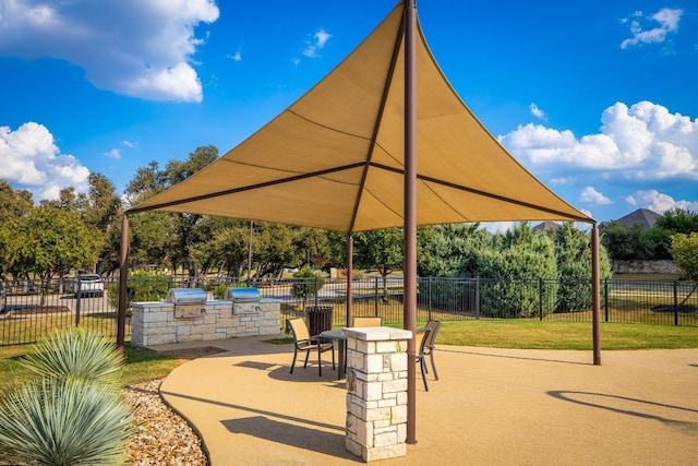 surrounding community with a patio and an outdoor kitchen