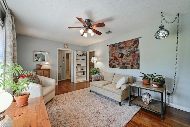 living room featuring dark hardwood / wood-style floors, ceiling fan, and a textured ceiling