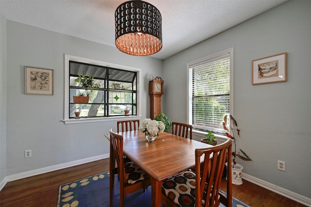 dining room with a textured ceiling, an inviting chandelier, and dark wood-type flooring