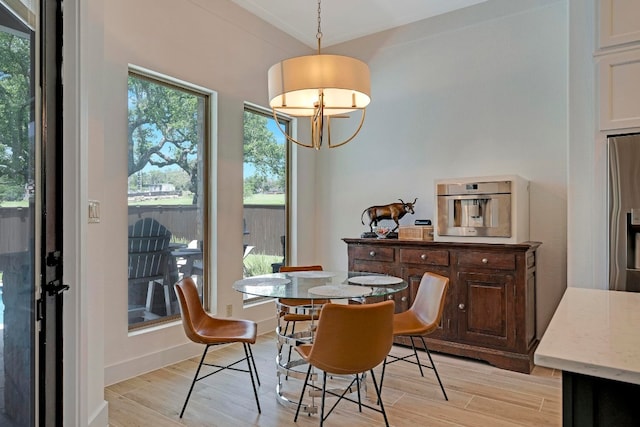 dining space with crown molding, light hardwood / wood-style flooring, and a notable chandelier