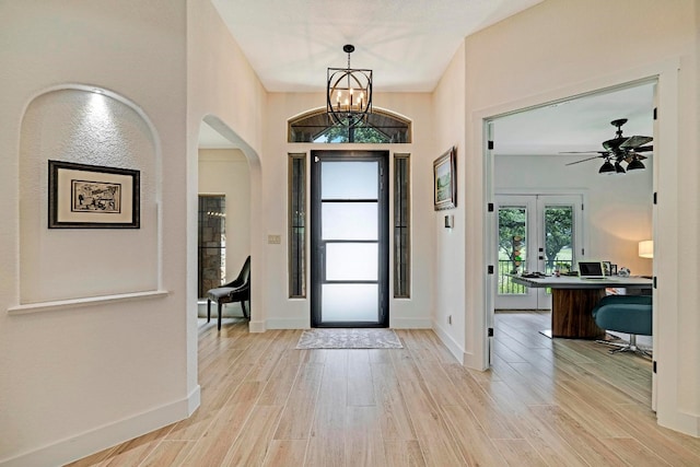 entryway with ceiling fan with notable chandelier, light hardwood / wood-style flooring, and french doors