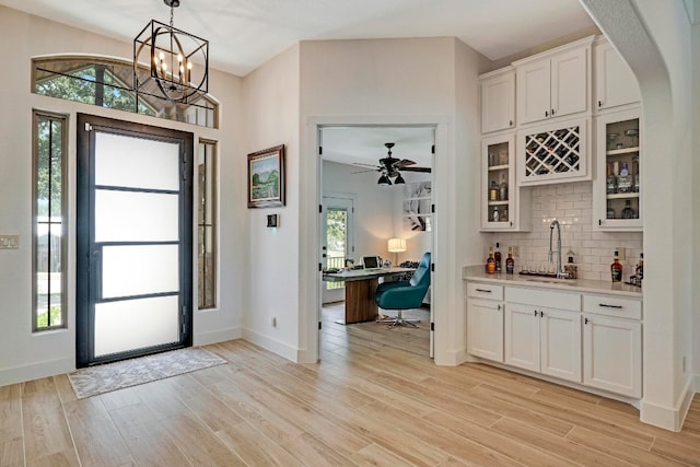 entrance foyer with ceiling fan with notable chandelier, light hardwood / wood-style flooring, and plenty of natural light