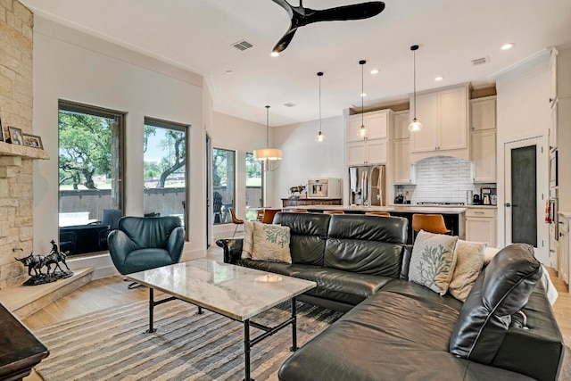 living room featuring ornamental molding, light wood-type flooring, and ceiling fan