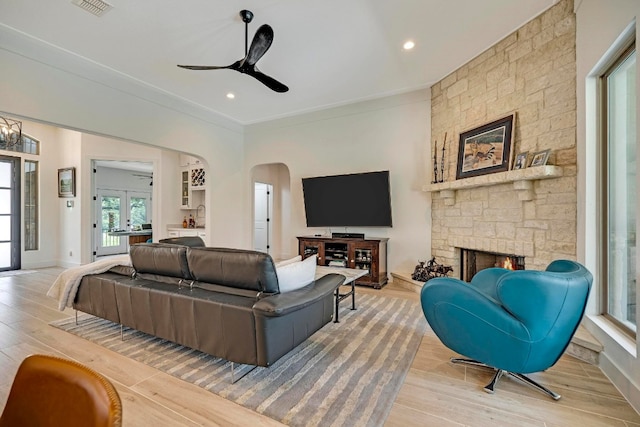 living room with ceiling fan, ornamental molding, a fireplace, and light hardwood / wood-style floors