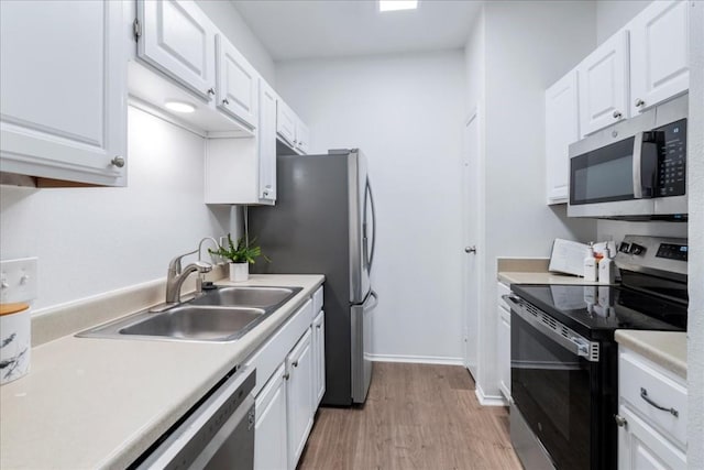 kitchen with sink, stainless steel appliances, white cabinets, and light wood-type flooring