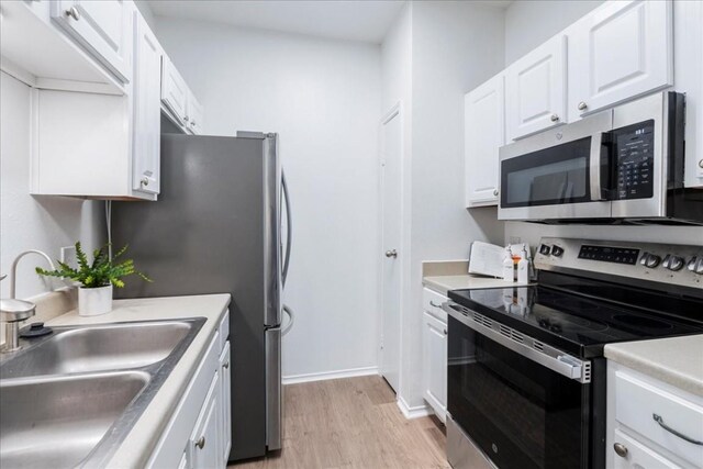 kitchen featuring sink, appliances with stainless steel finishes, light hardwood / wood-style floors, and white cabinetry