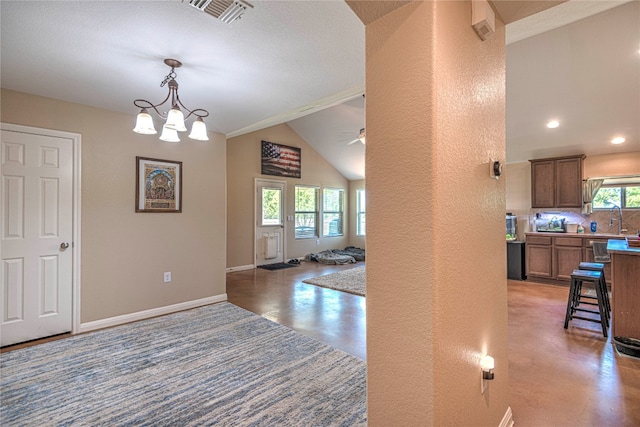 corridor with a notable chandelier, sink, and vaulted ceiling