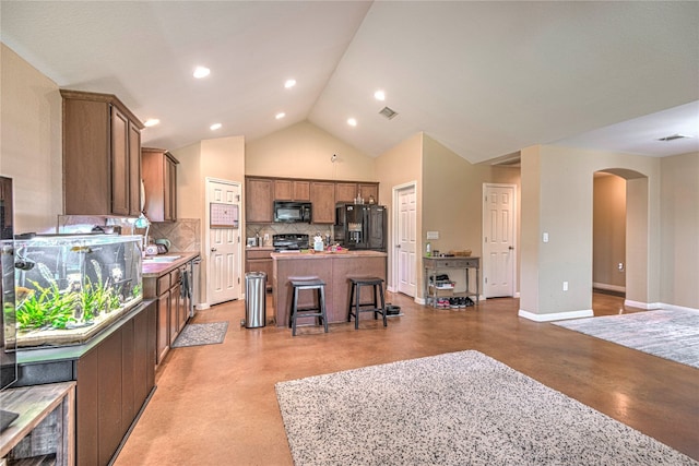 kitchen featuring lofted ceiling, a kitchen island, black appliances, a breakfast bar area, and decorative backsplash