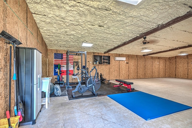 exercise room featuring concrete floors and an AC wall unit