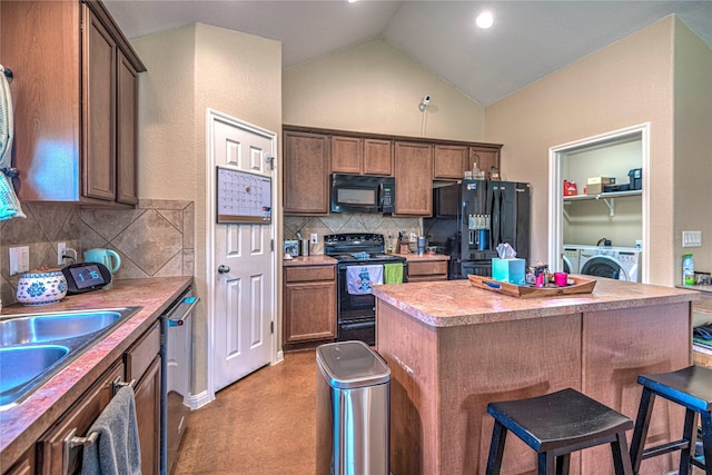 kitchen with backsplash, black appliances, independent washer and dryer, light colored carpet, and vaulted ceiling