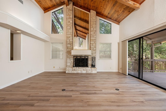 unfurnished living room with wood ceiling, beamed ceiling, wood finished floors, and a stone fireplace