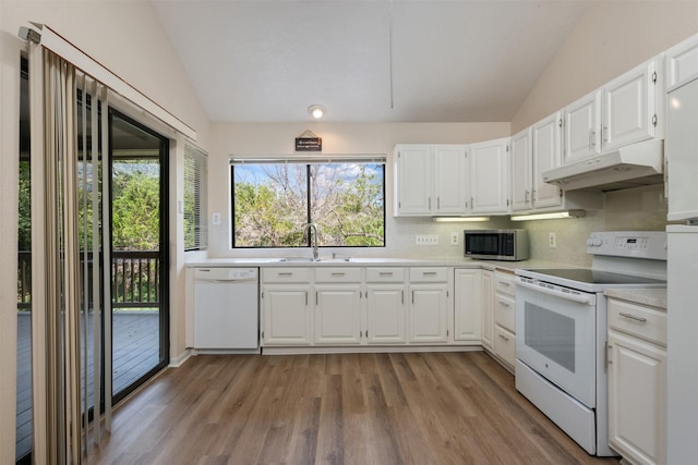 kitchen with lofted ceiling, under cabinet range hood, white appliances, and a sink