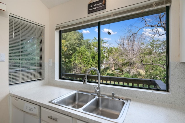 kitchen with dishwasher, light countertops, a sink, and white cabinets