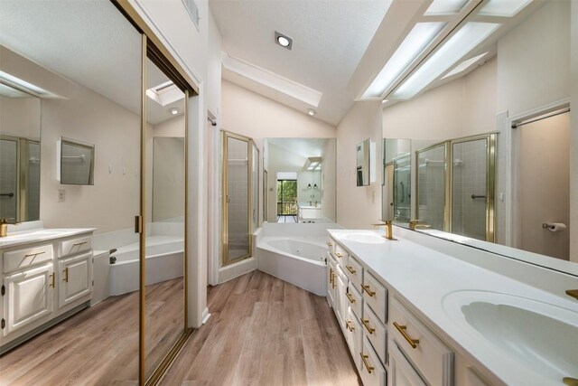 full bath featuring vaulted ceiling with skylight, a sink, wood finished floors, a shower stall, and a bath