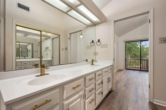 bathroom with hardwood / wood-style flooring, vanity, and lofted ceiling