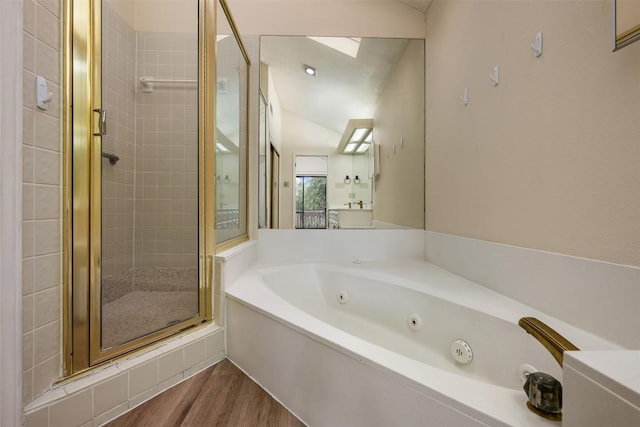bathroom featuring a tub with jets, a skylight, a shower stall, and wood finished floors