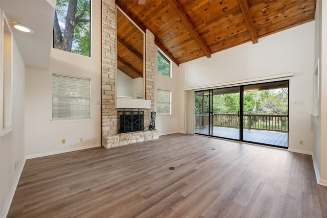 unfurnished living room featuring wood ceiling, hardwood / wood-style floors, beam ceiling, high vaulted ceiling, and a stone fireplace