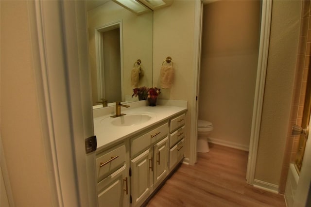 full bathroom with baseboards, vanity, toilet, and wood finished floors