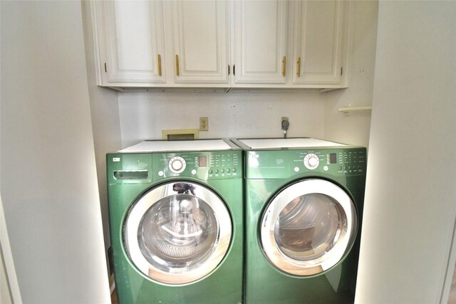 washroom with cabinets and washing machine and dryer