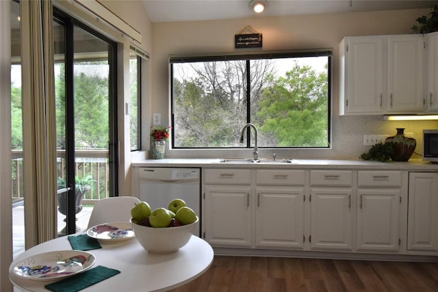 kitchen with white cabinets, light countertops, white dishwasher, and a sink