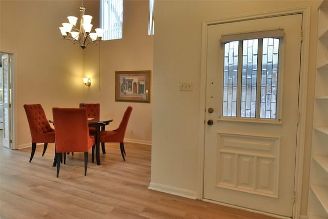 dining space with light wood-type flooring, a notable chandelier, and baseboards