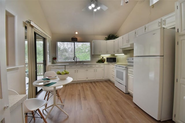 kitchen with light countertops, vaulted ceiling, a sink, and white appliances