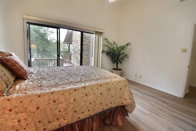 bedroom with light wood-style flooring, baseboards, and access to exterior
