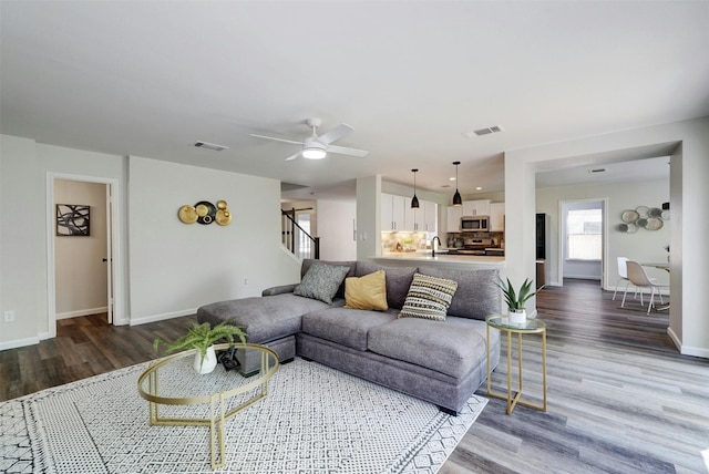 living room with wood-type flooring, sink, and ceiling fan