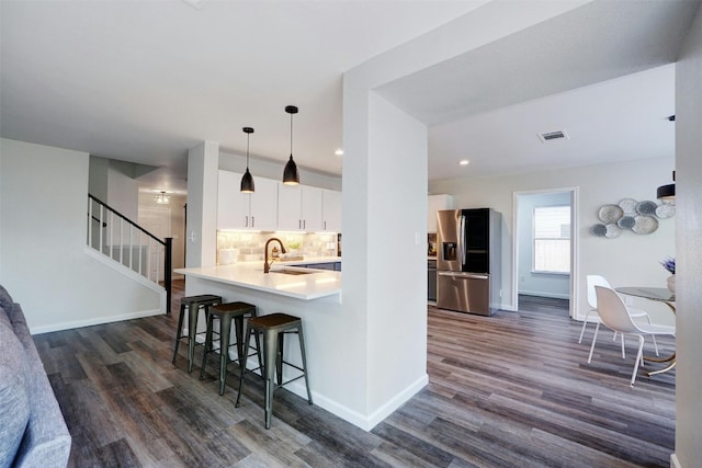 kitchen with stainless steel fridge, kitchen peninsula, dark wood-type flooring, and white cabinets