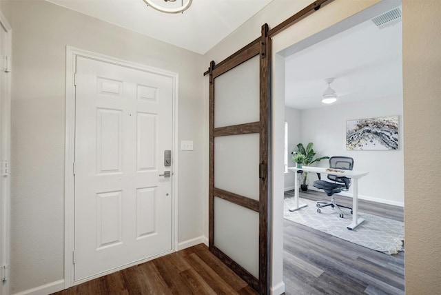 doorway to outside featuring ceiling fan, dark wood-type flooring, and a barn door