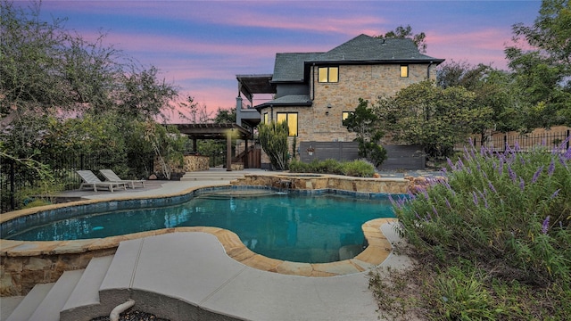 pool at dusk featuring a pergola and a patio