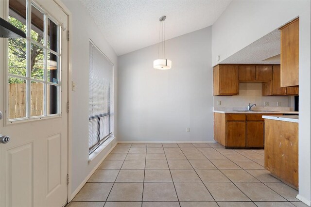 kitchen featuring pendant lighting, a textured ceiling, sink, high vaulted ceiling, and light tile patterned floors