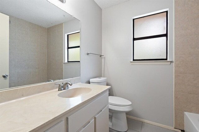 bathroom featuring a bathing tub, vanity, a textured ceiling, toilet, and tile patterned floors