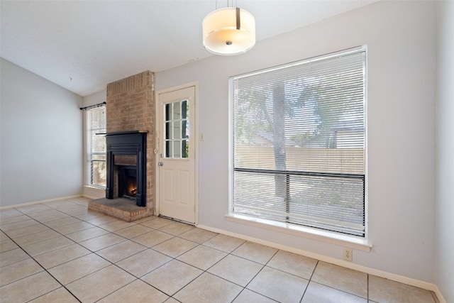 unfurnished living room featuring a fireplace, light tile patterned flooring, and lofted ceiling