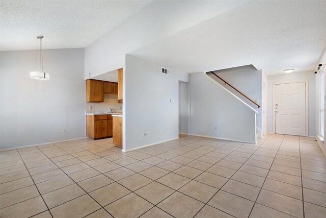 spare room with vaulted ceiling, a textured ceiling, light tile patterned floors, and sink