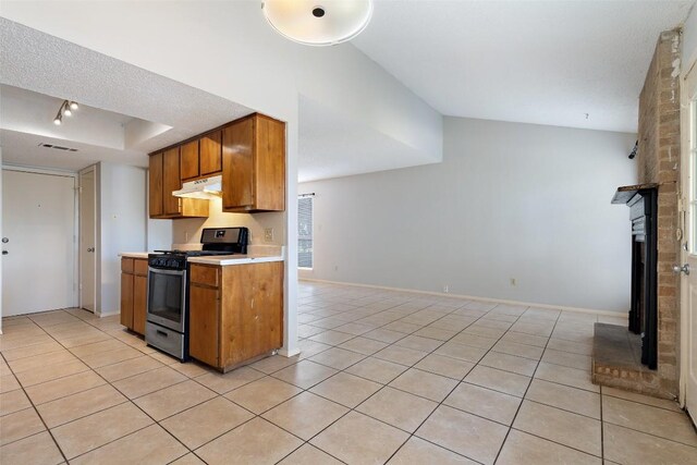 kitchen with a textured ceiling, vaulted ceiling, light tile patterned floors, and range with gas cooktop