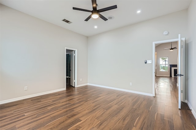 empty room with a towering ceiling, dark hardwood / wood-style flooring, and ceiling fan