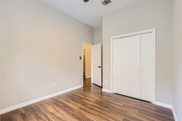 unfurnished bedroom featuring a towering ceiling, dark hardwood / wood-style floors, and a closet