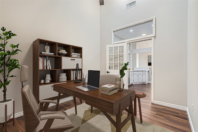 home office featuring sink, a towering ceiling, and dark wood-type flooring