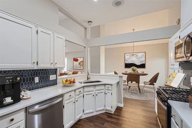 kitchen with pendant lighting, white cabinets, sink, dark hardwood / wood-style floors, and stainless steel appliances