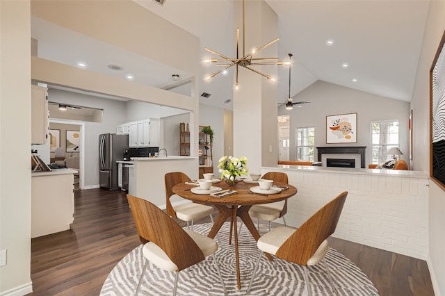 dining space with ceiling fan with notable chandelier, dark wood-type flooring, and high vaulted ceiling