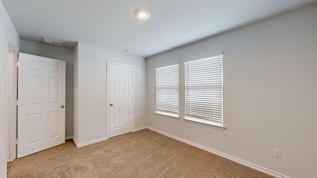 unfurnished bedroom with light carpet and a closet