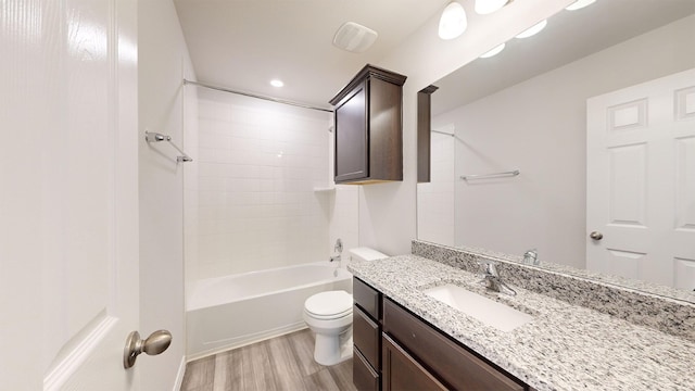 full bathroom with vanity, hardwood / wood-style flooring, tiled shower / bath combo, and toilet