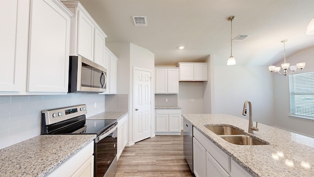 kitchen featuring stainless steel appliances, light stone counters, white cabinets, and sink