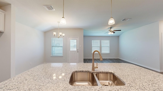 kitchen featuring wood-type flooring, light stone counters, sink, ceiling fan with notable chandelier, and vaulted ceiling