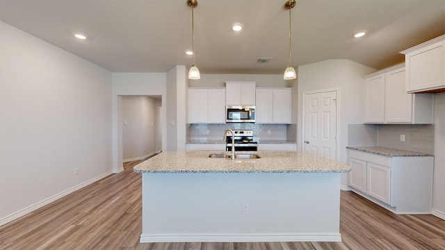 kitchen featuring appliances with stainless steel finishes, hanging light fixtures, light hardwood / wood-style floors, and white cabinets