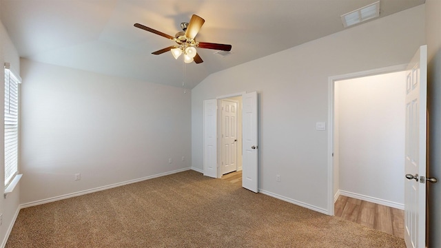 unfurnished bedroom with multiple windows, vaulted ceiling, ceiling fan, and light colored carpet