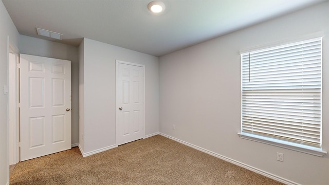 unfurnished bedroom with light carpet and a closet