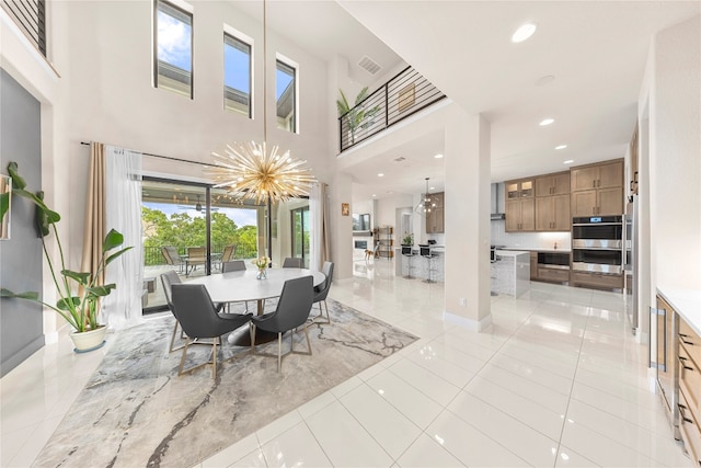 tiled dining space featuring an inviting chandelier and a high ceiling