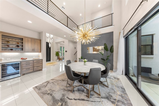 dining room featuring an inviting chandelier, a high ceiling, wine cooler, and light tile patterned floors